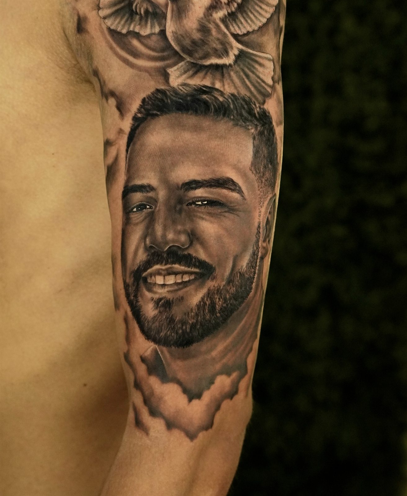 Black and grey portrait tattoo of a man with doves
