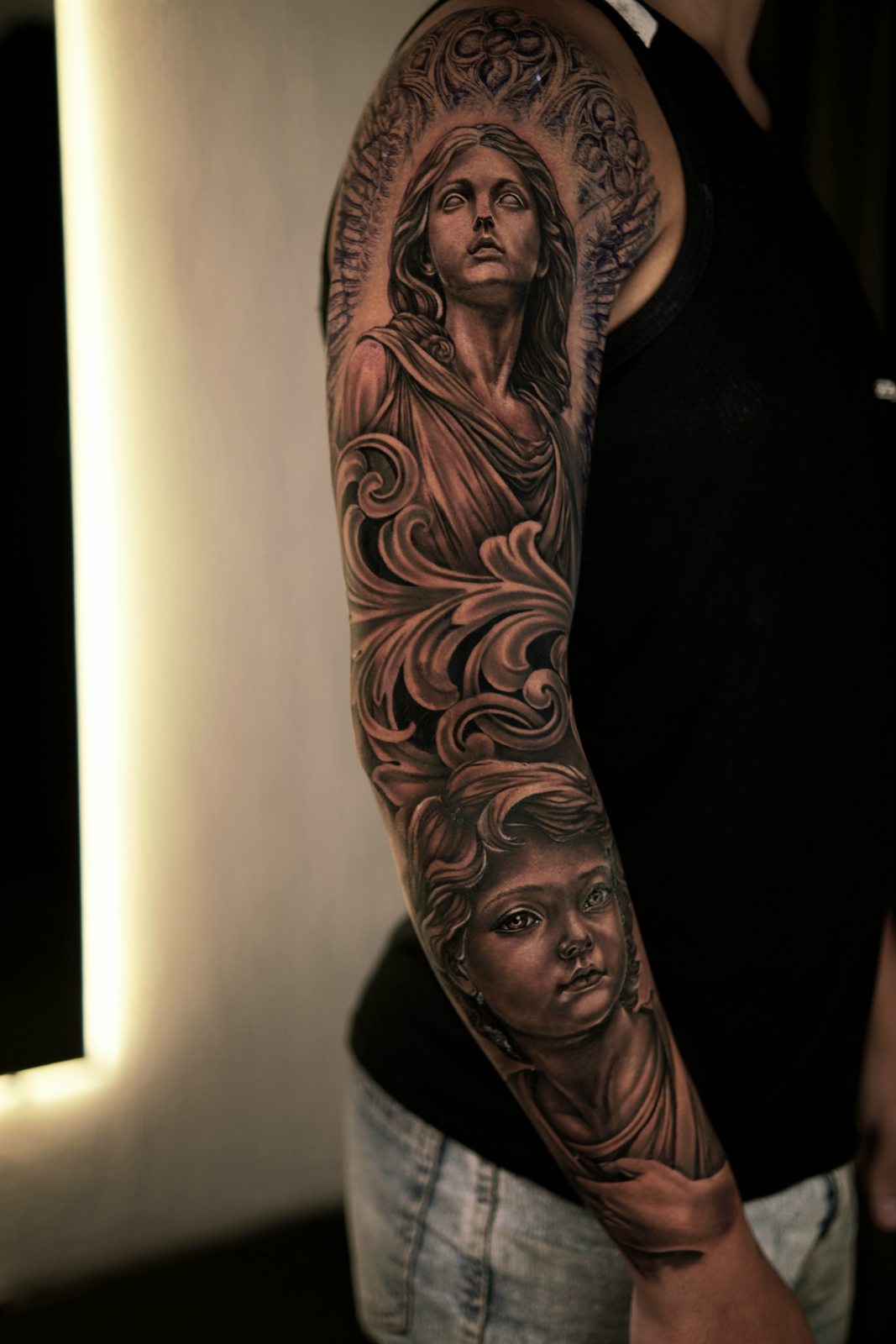 Full sleeve tattoo of an angel statue and child with filigree
