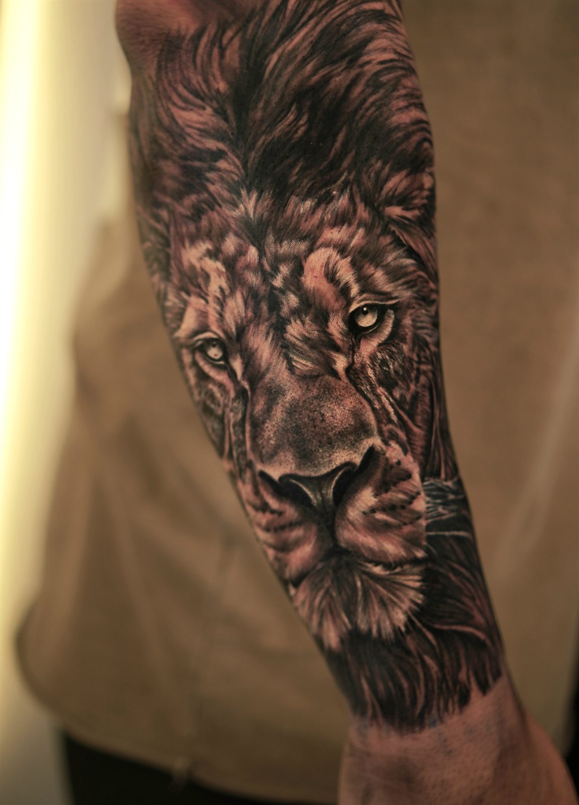 Realistic lion face tattoo on a forearm
